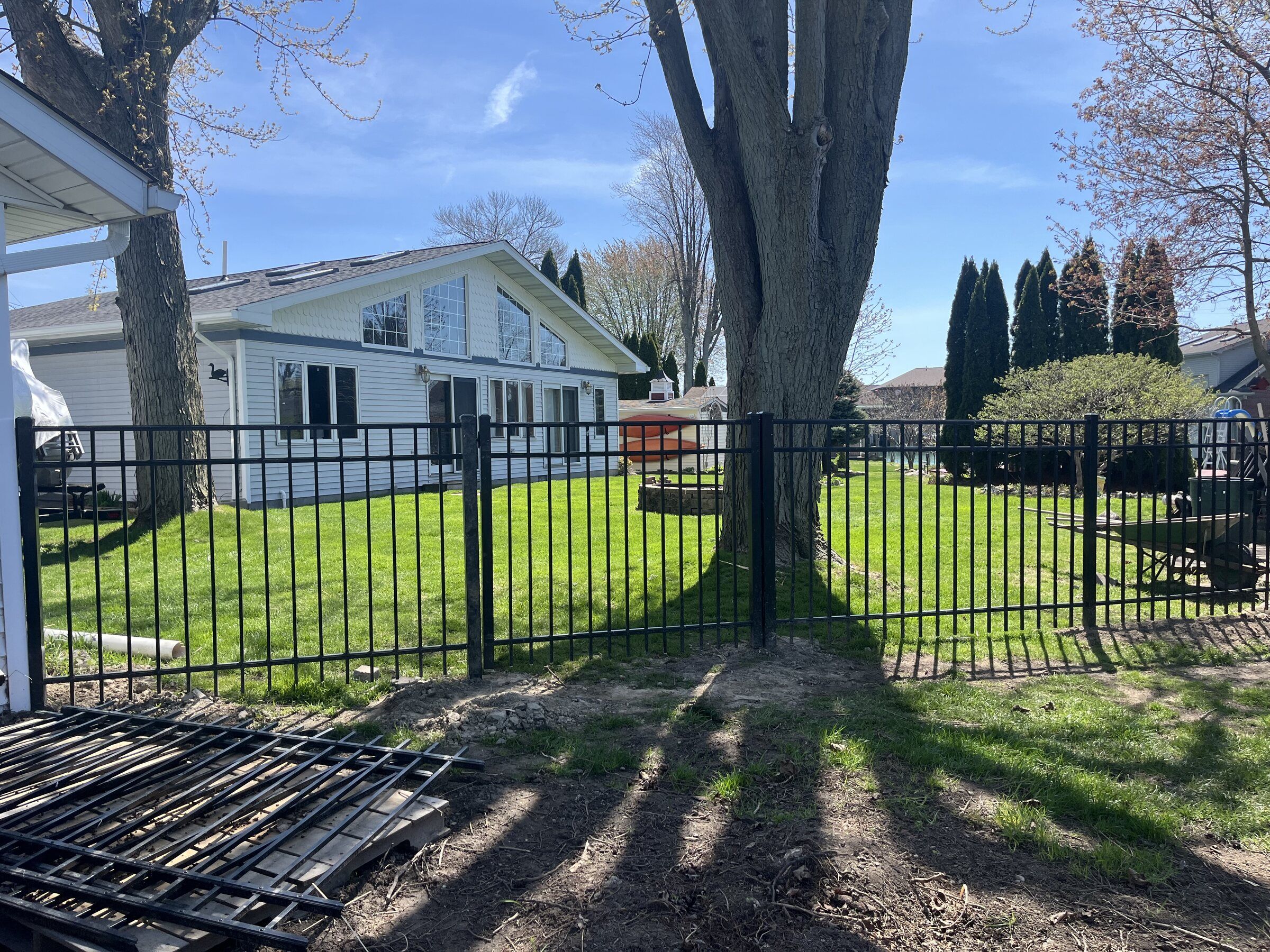 Black aluminum fence enclosing a backyard lawn