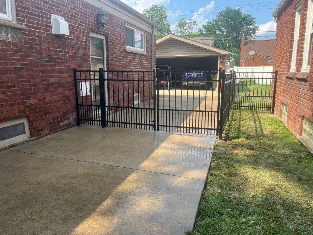 Black aluminum fence and double drive gate leading to a detached garage