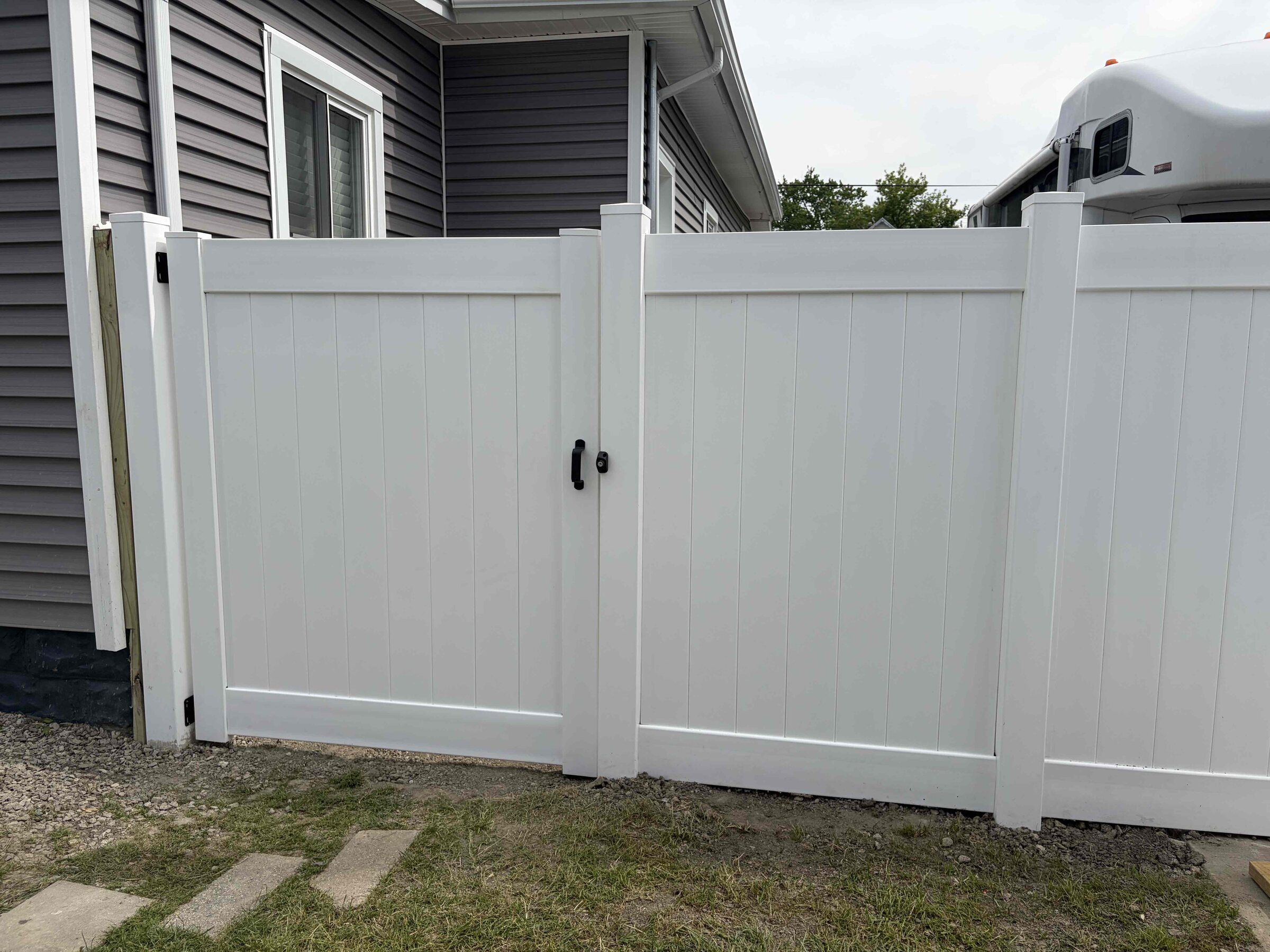 White vinyl privacy fence with a single walk gate