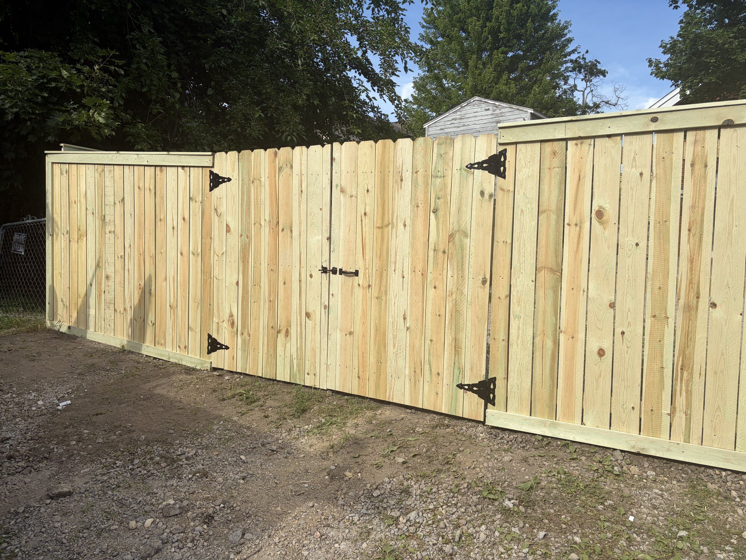 New wood privacy fence with a double drive gate on black strap hinges